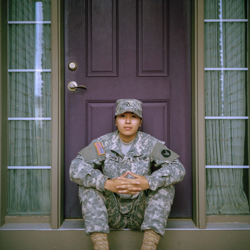 A military member sitting in front of a door.